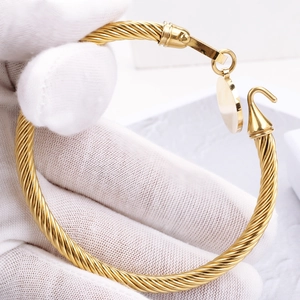 Bracelet torsadé doré avec fermoir fer à cheval et pendentif rond en métal poli