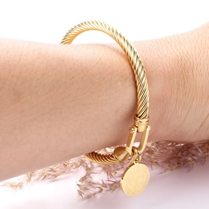 Bracelet câble en acier doré avec pendentif médaille de Saint Benoît en gros plan