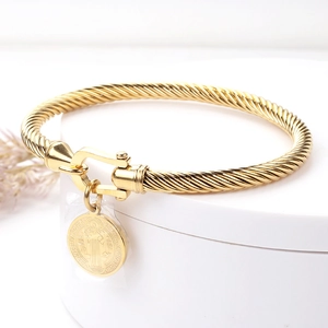 Détail du bracelet torsadé doré avec fermoir fer à cheval et médaille Saint-Benoît