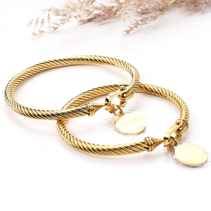 Détail de deux bracelets torsadés dorés avec fermoir fer à cheval et pendentif pièce