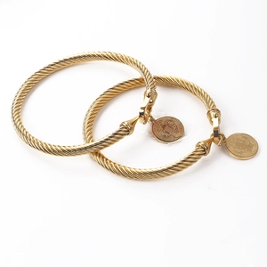 Détail d'un bracelet torsadé doré avec pendentifs religieux et fermoir à fer à cheval
