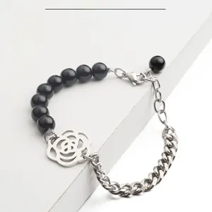 Détail d'un bracelet en perles d'agate noire avec pendentif en forme de rose creuse