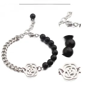 Vue détaillée du pendentif rose ajouré et du rang de perles noires sur le bracelet en acier