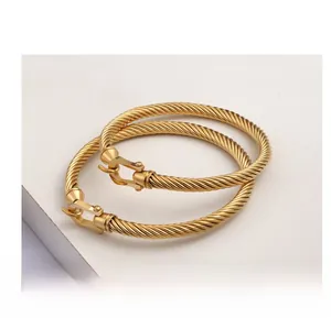 Macro shot of gold and silver cable bracelets with horseshoe shackle clasp detailing