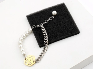 Détail du bracelet en perles et chaîne gourmette avec breloque fleur de camélia