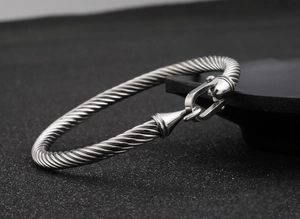 Macro detail of silver twisted cable bracelet featuring industrial horseshoe buckle clasp