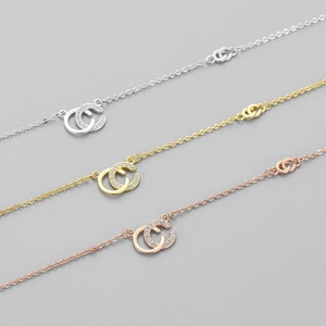 Détail de pendentifs en C entrelacés en or, argent et or rose sertis de cristaux pavés