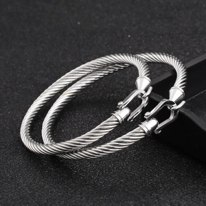Close-up of silver cable twist bracelets featuring horseshoe buckle and detailed steel texture