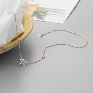 Détail d'un collier en or rose avec pendentif double anneau serti de zircons brillants