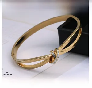Détail d'un bracelet doré en forme de C torsadé avec cristaux au style minimaliste