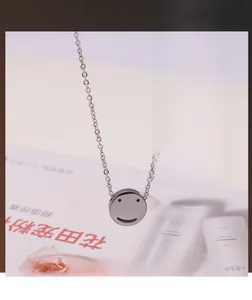 Close-up of polished silver smiley face pendant on a thin link chain over a magazine