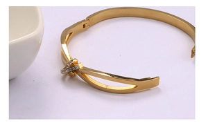 Détail du bracelet en acier inoxydable doré avec un design croisé orné de strass brillants