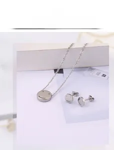 Detail view of smiley face pendant necklace and matching stud earrings set in silver finish