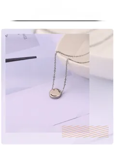 Close-up of a silver smiley face necklace pendant on a delicate chain over a ceramic plate