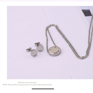 Detailed view of smiley face jewelry set with stud earrings and necklace in silver titanium