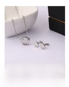 Detail view of a minimalist smiley face jewelry set with thin necklace and stud earrings