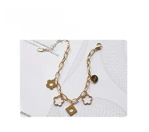 Detail of a gold-plated charm bracelet with floral motifs and Lucky engraved tag