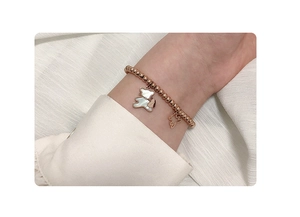 Detail of rose gold beaded bracelet with mother of pearl bear pendants on wrist