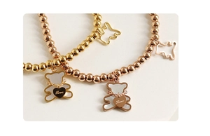 Detailed close-up of beaded bracelets with bear charms in gold and rose gold finishes