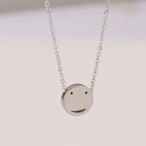 Minimalist silver smiley face pendant necklace with fine chain on beige background