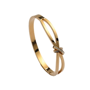 Bracelet jonc croisé plaqué or élégant avec cristaux micro-pavés sur fond blanc neutre