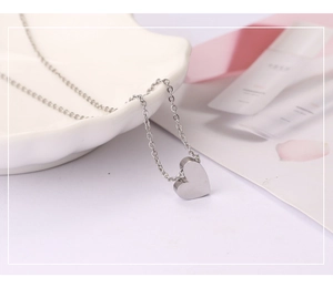 Détail d'un collier pendentif coeur en argent poli sur un coquillage décoratif