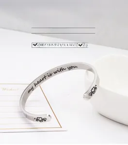 Close-up of engraved inspirational quote my heart is with you on silver cuff bracelet