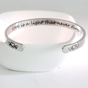 Macro view of C-shaped stainless steel bracelet with engraved inspirational quote