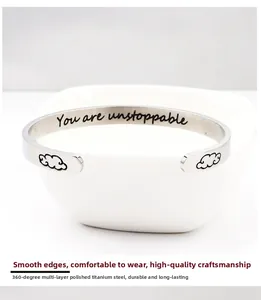 Macro shot of silver C-shaped cuff bracelet with You Are Unstoppable engraving
