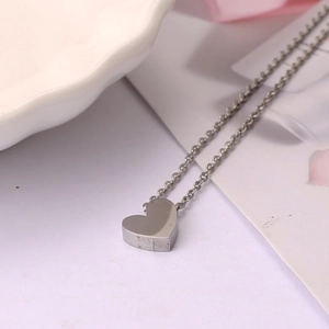 Collier avec pendentif cœur argenté poli et chaîne fine exposé sur une assiette