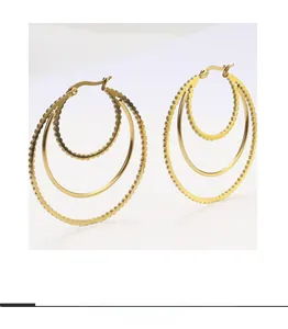 Detailed view of triple-layered gold hoop earrings with wave textures and polished finish