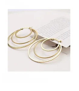 Macro detail of triple-layer gold earrings with beaded and polished steel texture