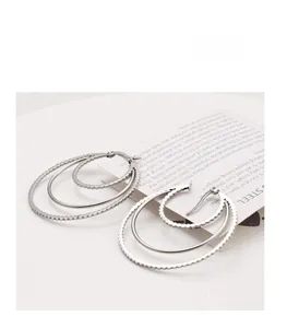 Close-up of triple-layered silver stainless steel hoop earrings with textured beaded edges