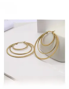 Detailed macro of triple-layer gold hoop earrings with a mirror-polished finish