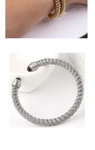 Detail of twisted cable stainless steel bangles with black bead ends in gold and silver