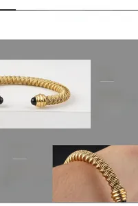 Macro shot of gold-plated twisted cable bracelet with black spherical beads on the ends
