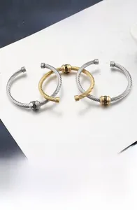 Detail of 18K gold and silver stainless steel cable bracelets with Greek Key pattern beads