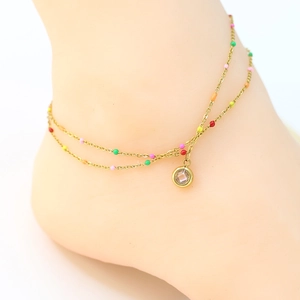 Close-up of double-layer gold anklet with colorful beads and a clear crystal pendant