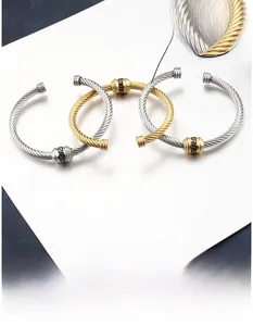 Macro detail of twisted cable bangles with Greek key patterns in gold and silver steel