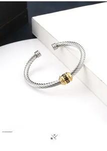 Detail of twisted cable steel bangle with golden Greek meander pattern bead