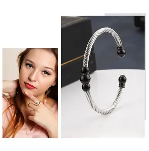 Macro detail of silver twisted cable bracelet featuring five polished black beads on a stand