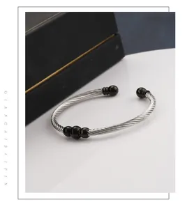 Detail of silver twisted cable steel bracelet with black beads on a jewelry display stand
