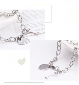 Macro detail of silver stainless steel chain with heart love and key charms on a tray
