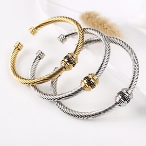Macro shot of 18K gold and silver cable cuff bracelets featuring Greek key pattern details
