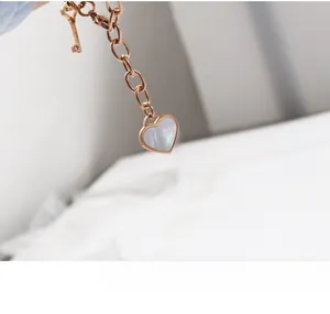 Close-up of rose gold bracelet with heart shell pendant and small key charm