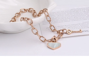 Detail of rose gold heart shell pendant and key charm on stainless steel chain