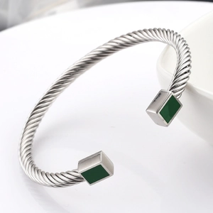Gepolijste roestvrijstalen gedraaide kabelarmband met groene vierkante edelsteenaccenten