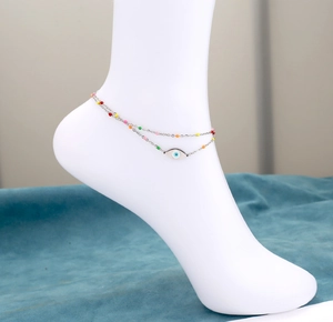 Detail eines silbernen Boho-Fußkettchens mit bunten Perlen und Evil-Eye-Anhänger