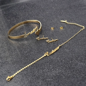 Detailed close-up of custom gold name necklace, heart bracelet, and earrings set