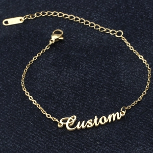 Customized gold name bracelet in cursive script on a blue textured background